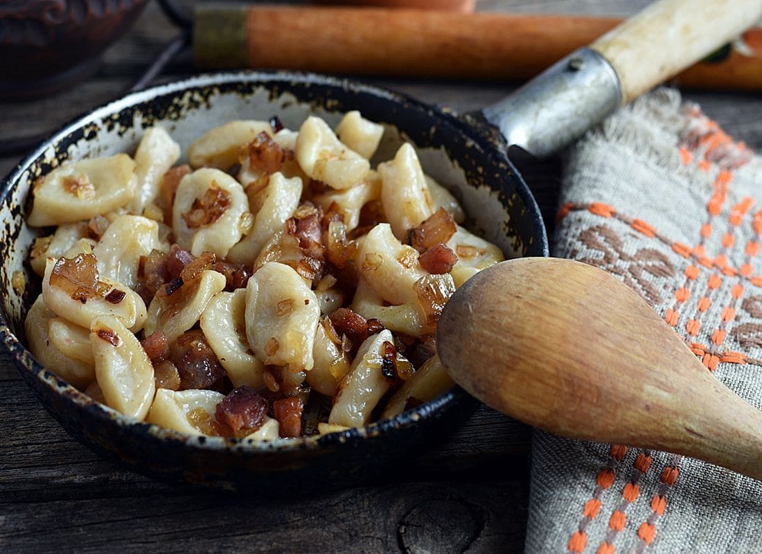 Traditional halushki dumplings mixed with crispy bacon bits served in a rustic iron skillet