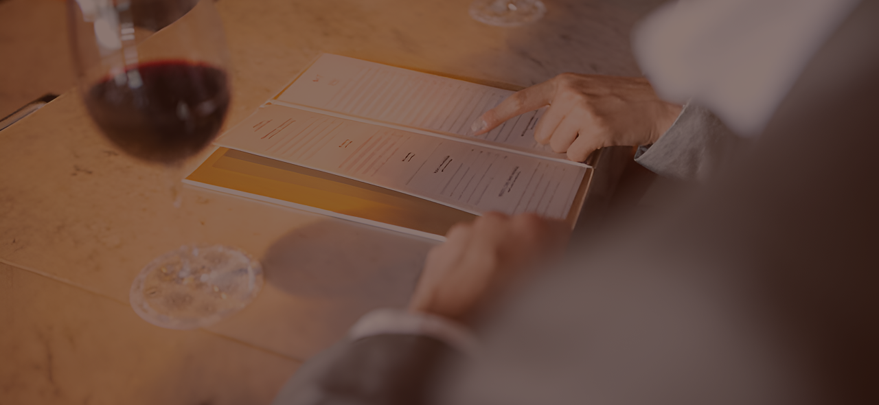 Close-up of two people sitting at a counter and looking at a menu card.