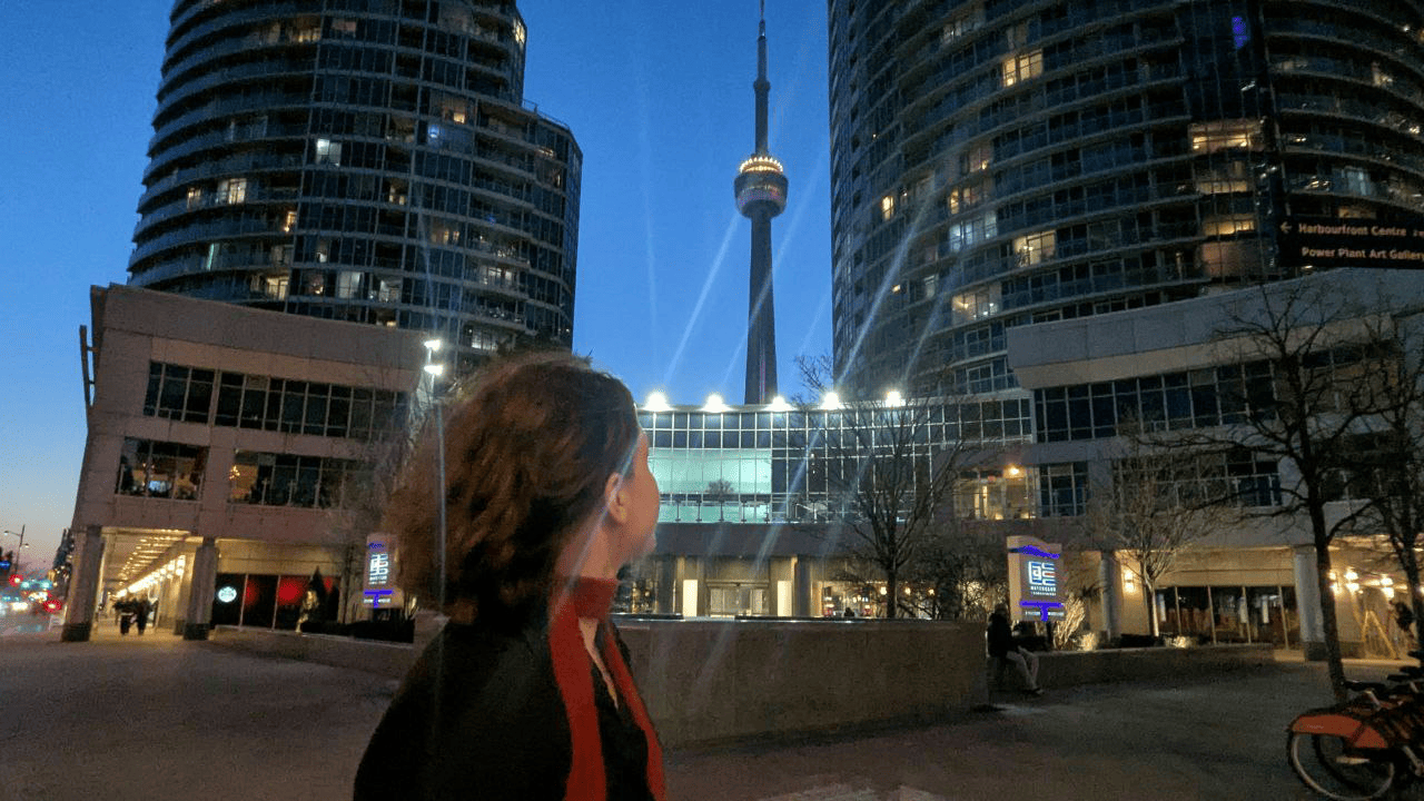 A girl wearing a red scarf stands with Toronto and the CN Tower in the background